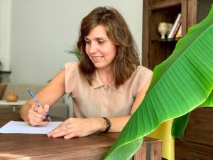 Marta Cela sentada a la mesa con papel y boli